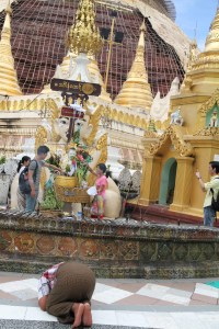 En Buddah-figur tilbes av flere personer. I forgrunnen ligger en mann og ber.
