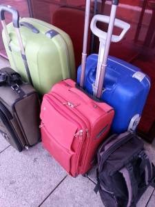 Bilde av en grønn, blå, militærgrønn og rød koffert, samt en sort ryggsekk.