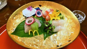 Gullfarget fat med rå fisk, dandert med blomster og pynt.