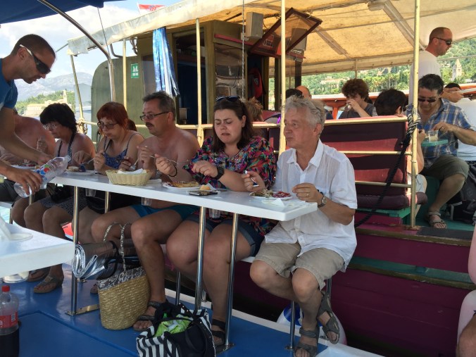 På båttur personer på en båt, sittende på en benk og spiser.