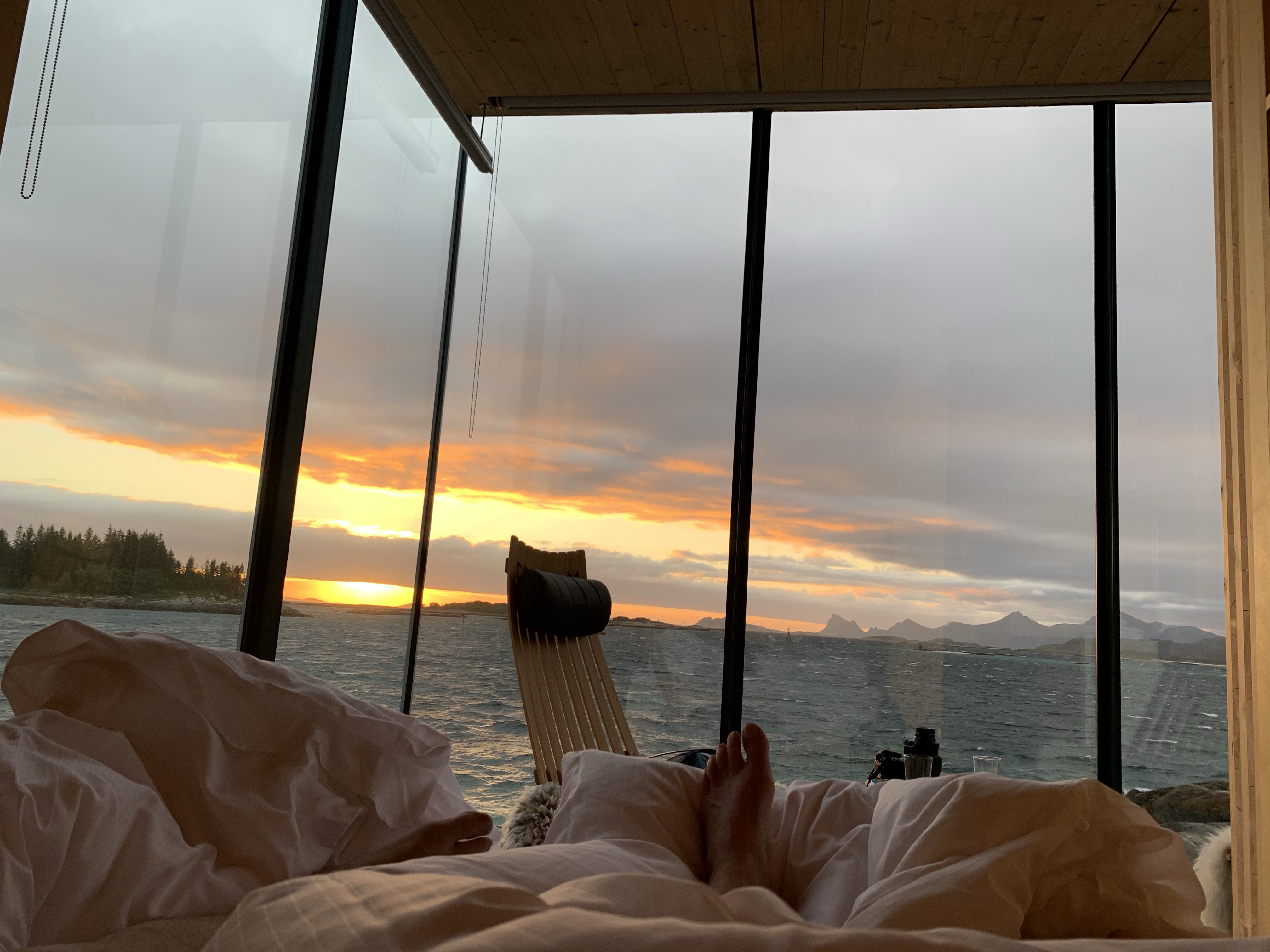 Bilde av fot på dyne og utsikt med midnattsol